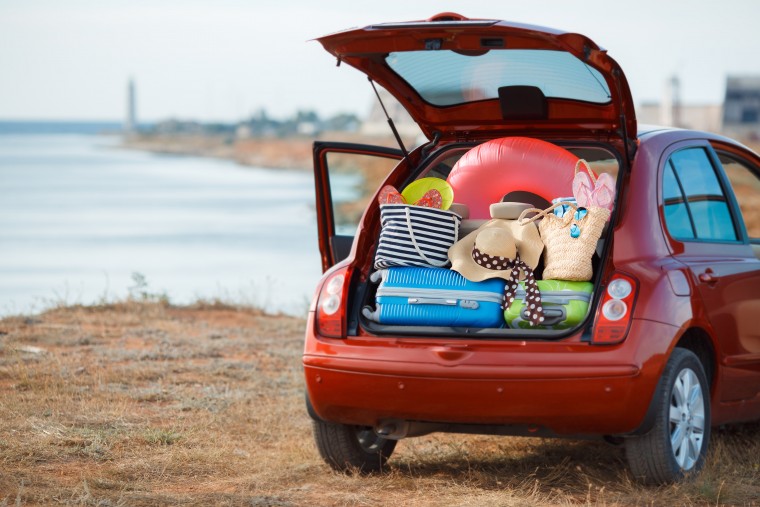 red car at beach packed with luggage and beach paraphernalia