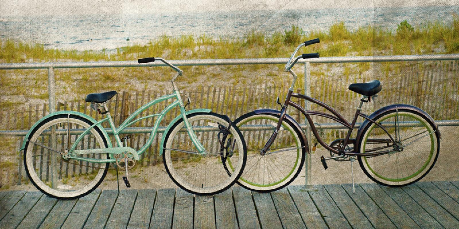 bikes leaning against the railing on the boardwalk with the dunes and beach in the background