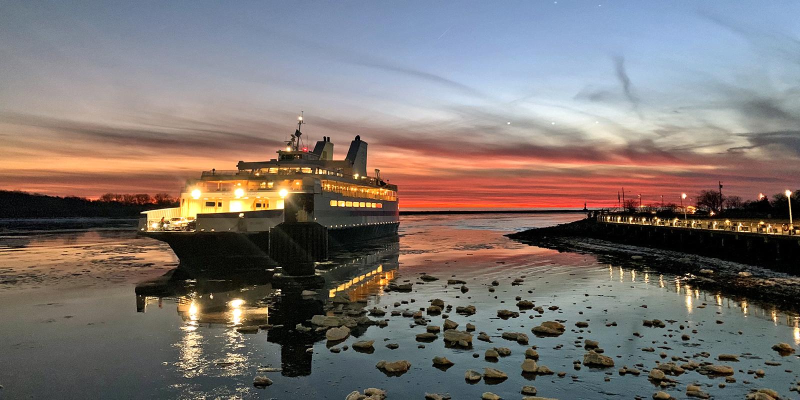 The Cape May-Lewes Ferry arrives on an icy bay with a beautiful red sky and sunset in the background