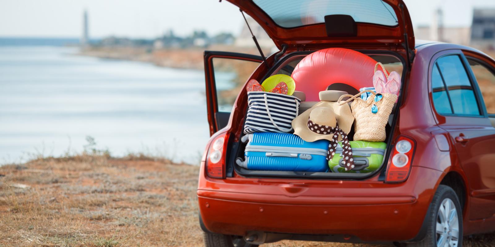 red car at beach packed with luggage and beach paraphernalia