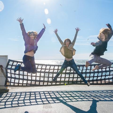 Three women jumping for joy aboard the Cape May-Lewes Ferry