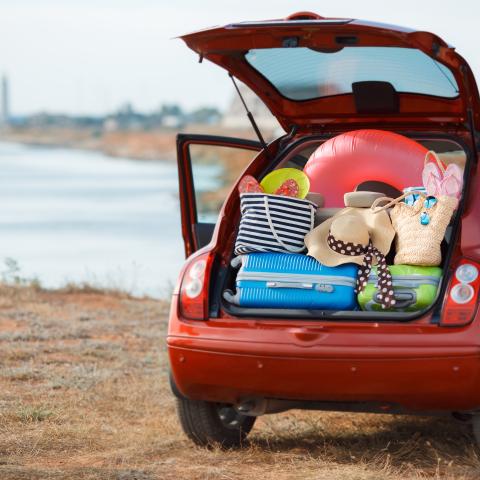 red car at beach packed with luggage and beach paraphernalia