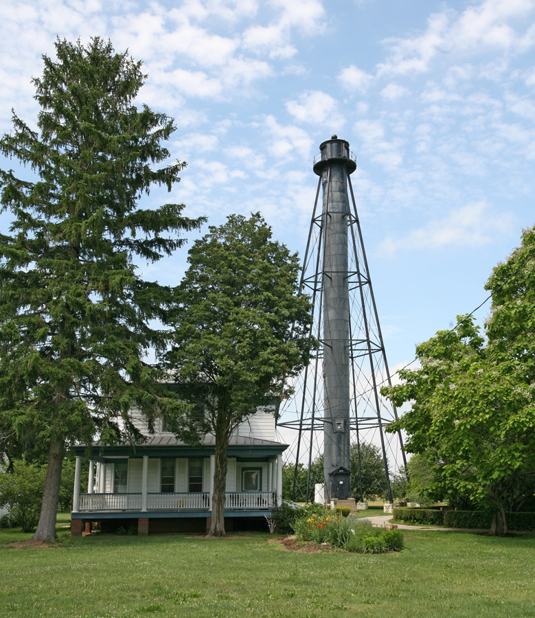 The tall black skeletal light house tower stands behind a house. Photo from Kraig Anderson, Light House Friends (https://www.lighthousefriends.com/light.asp?ID=463)