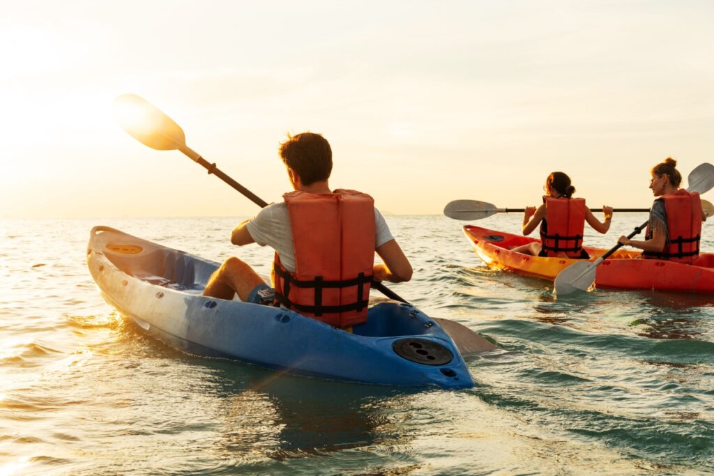 Group of kayakers kayaking in the ocean at sunset