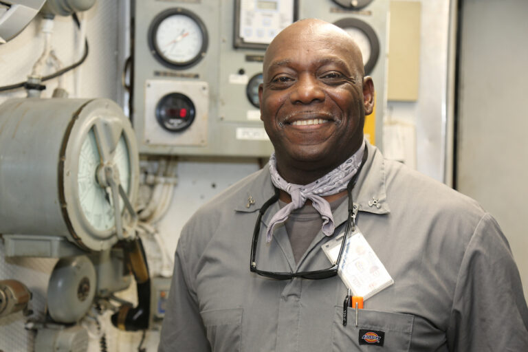 Ferry engineer smiles for the camera under the vessel