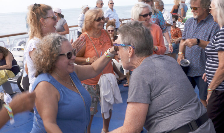 two ladies dance with one another, hand-in-hand, on the Ferry during the Rock the Boat event