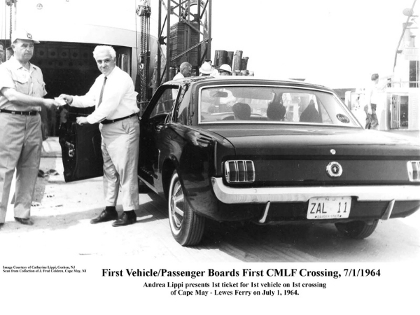 Historical black and white photo from July 1, 1964, showing Andrea Lippi presenting the first ticket to the driver of a black 1964 Ford Mustang, the first vehicle to board the Cape May-Lewes Ferry.
