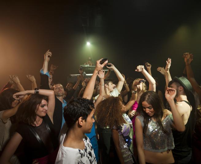 A large group of young adults dancing at a dark club