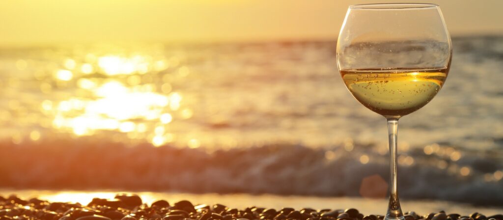 Image advertising the Cape May-Lewes Ferry's sunset wine cruises, showing a glass of white wine against the warm, golden light of the sun setting over the water.