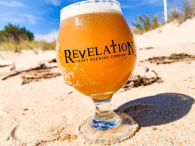 Snifter of Revelation Craft Brewing beer on a sandy beach