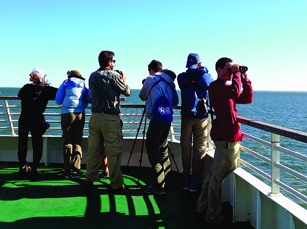 A group of birders with binoculars aboard the Cape May-Lewes Ferry