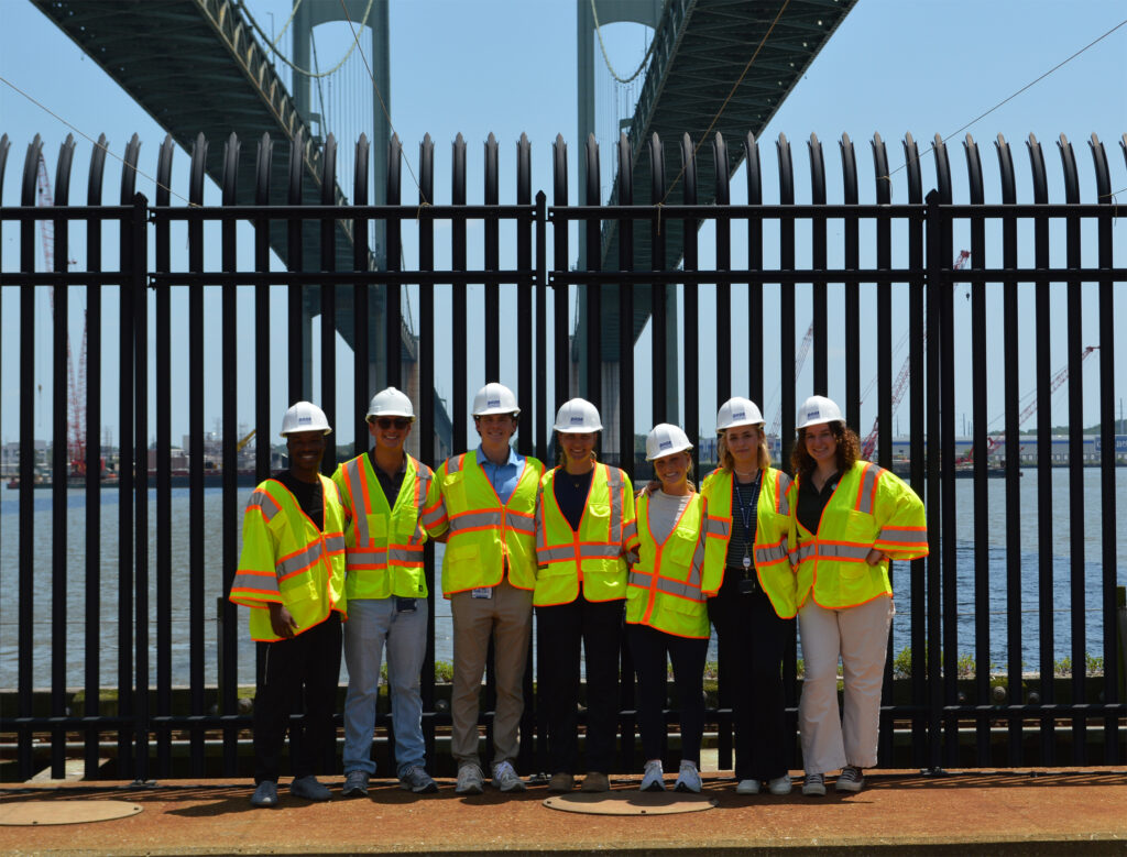 2025 DRBA Interns standing on one of the Delaware Memorial Bridge anchors with the twin spans above and behind them