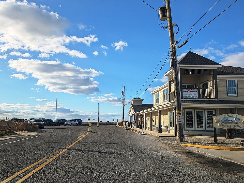 Road leading toward Sunset Beach, NJ with a Cape May Winery and Vineyard storefront and a Welcome to Sunset Beach sign visible on a clear day. Photo by Mr. Matté (https://commons.wikimedia.org/wiki/File:Cape_May_CR_606_wb_at_Sunset_Beach,_NJ,_Nov._2025.jpg) , CC BY-SA 4.0 (https://creativecommons.org/licenses/by-sa/4.0) , via Wikimedia Commons.
