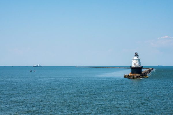 Wide shot photo of the Harbor of Refuge Lighthouse with the Cape-May Lewes Ferry Sailing in the background.