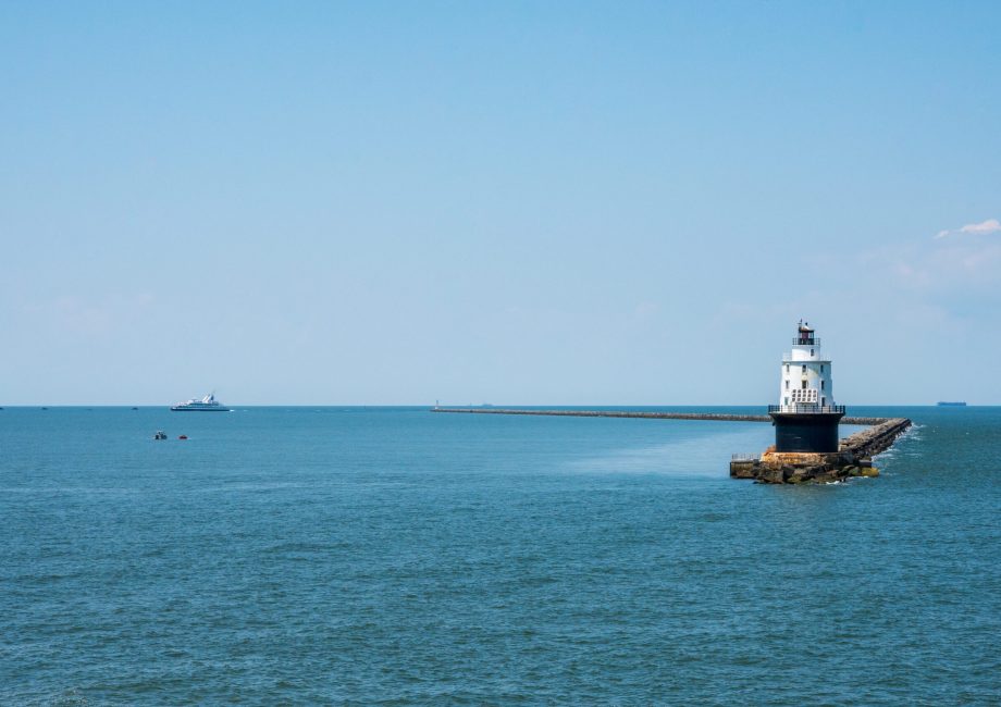 Wide shot photo of the Harbor of Refuge Lighthouse with the Cape-May Lewes Ferry Sailing in the background.