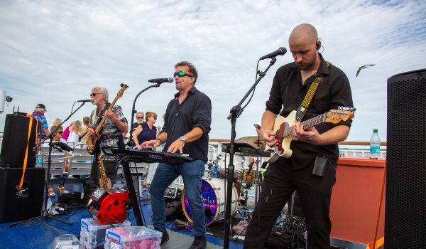 A singer and guitarists from Glass Onion perform on the Ferry during the Rock the Boat event
