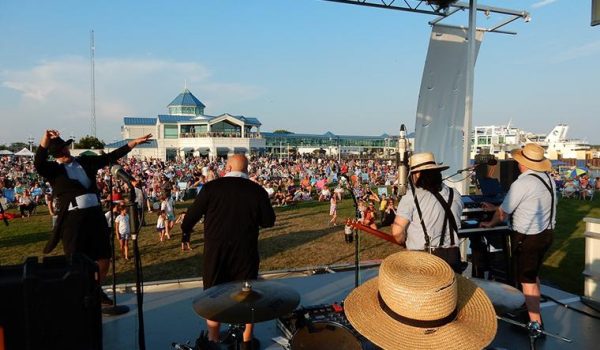 A packed lawn outside of Stowaways listens to the Amish Outlwas on stage at the Summer Concert Series